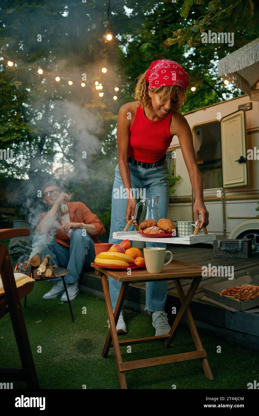 Amis heureux avec des boissons saines et des collations ayant barbecue partie au camping Banque D'Images