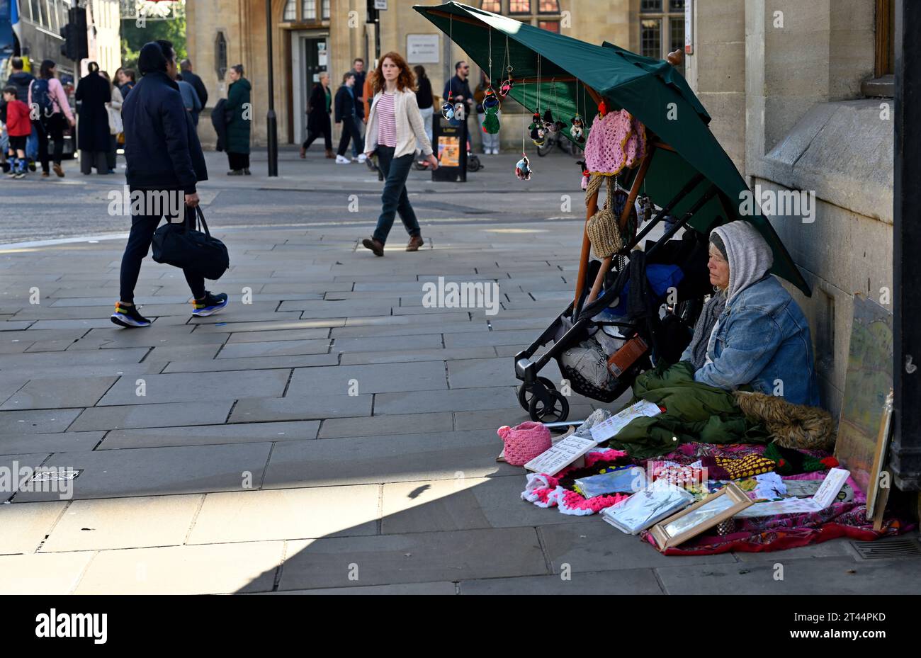 Une femme plus âgée a regroupé des articles vendant tout en étant assise sur le trottoir à Oxford, au Royaume-Uni Banque D'Images