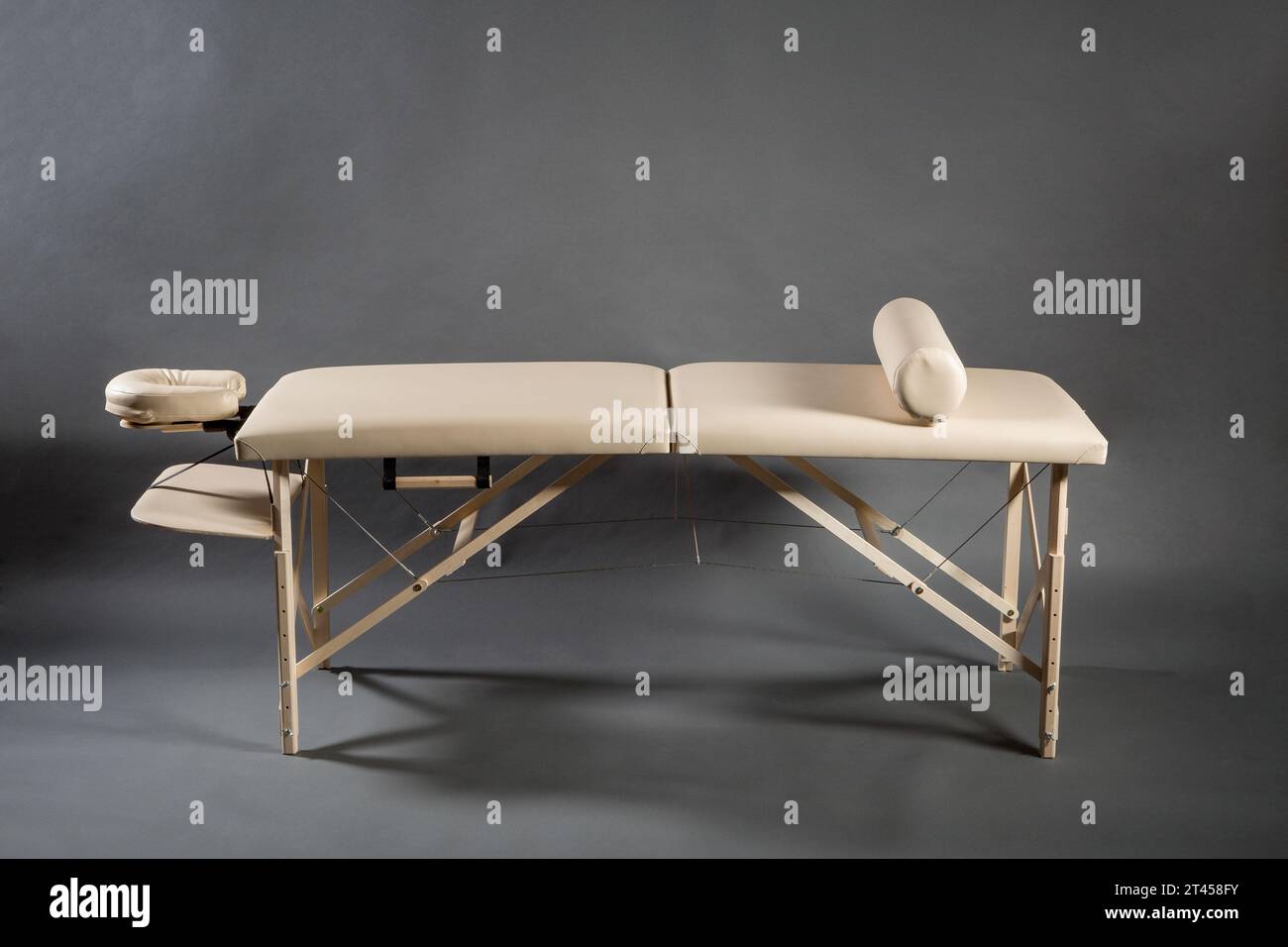 Table de massage pliante portable pour salle de traitement de physiothérapie sur le fond sombre. Banque D'Images