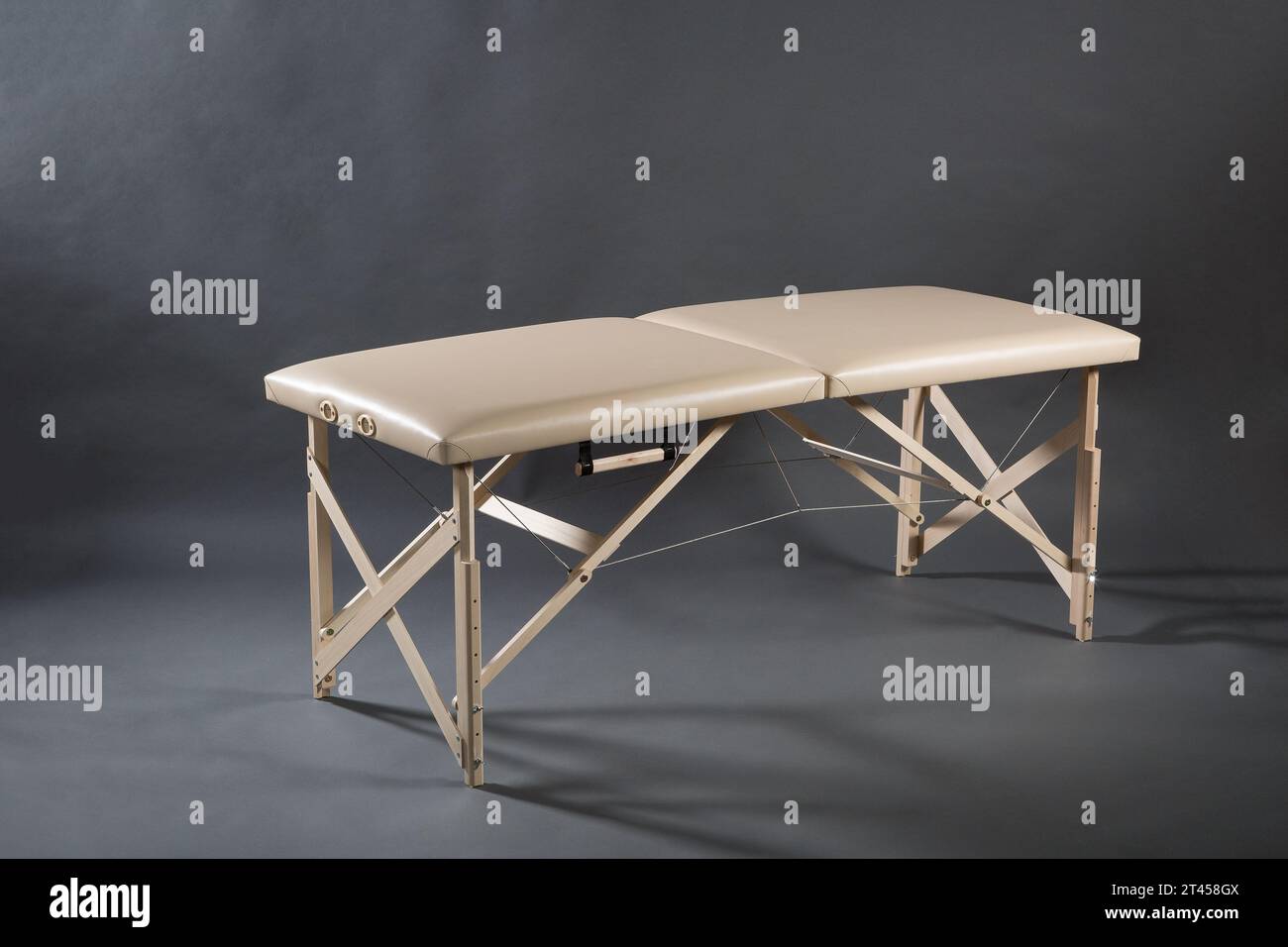 Table de massage pliante portable pour salle de traitement de physiothérapie sur le fond sombre. Banque D'Images