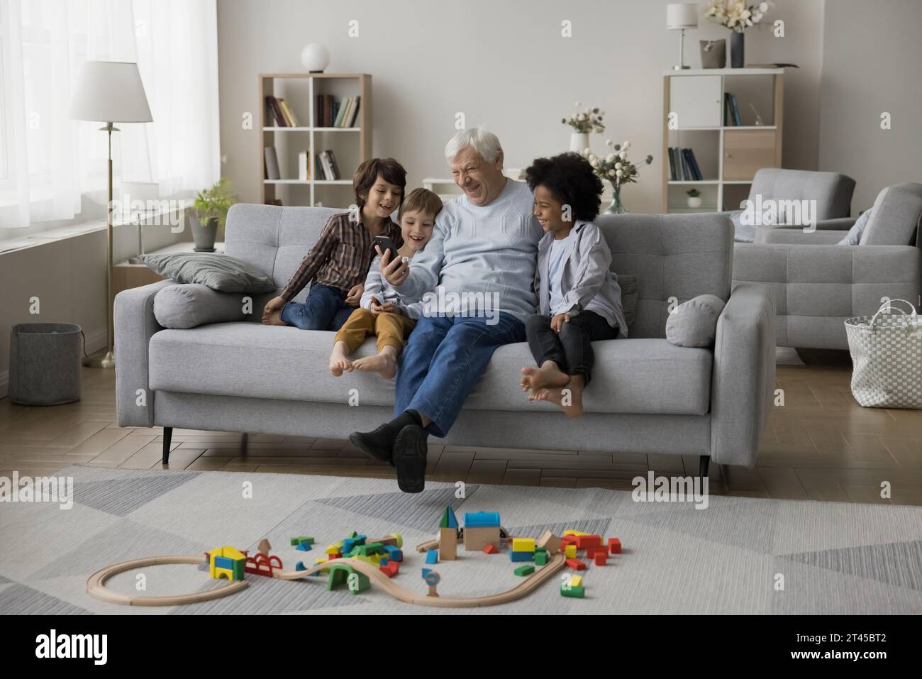Rire famille multigénérationnelle passer du temps à la maison en utilisant un smartphone Banque D'Images