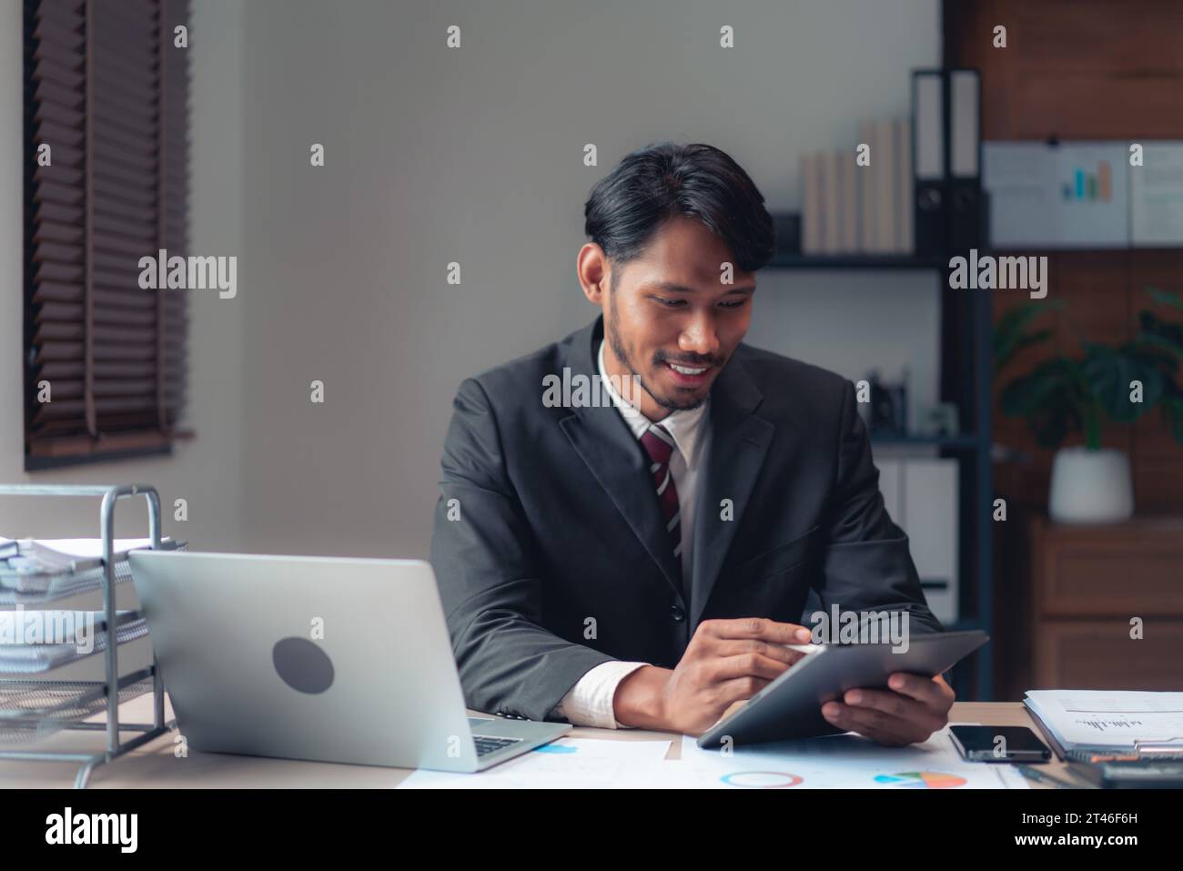 Homme d'affaires utilisant la tablette pour prendre des notes tout en vérifiant le rapport financier et comptable des affaires. Banque D'Images