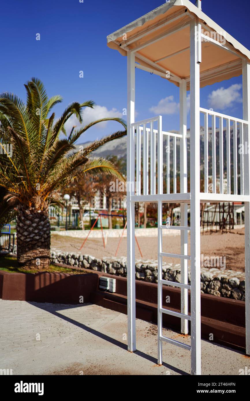 Poteau de garde-côtes en métal se dresse sur la plage près d'un palmier Banque D'Images