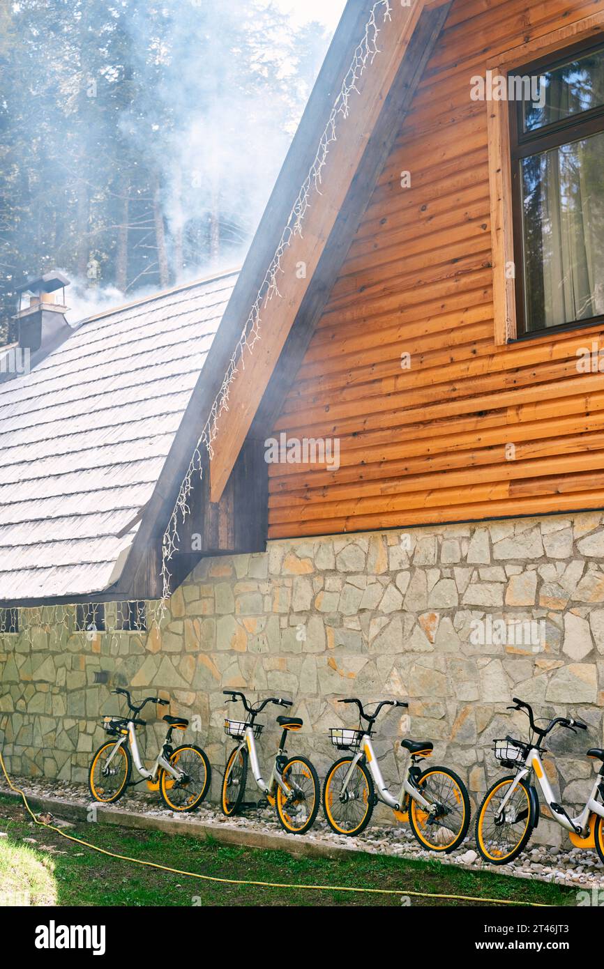 Rangée de vélos avec des paniers s'appuie contre le mur de pierre d'une maison Banque D'Images