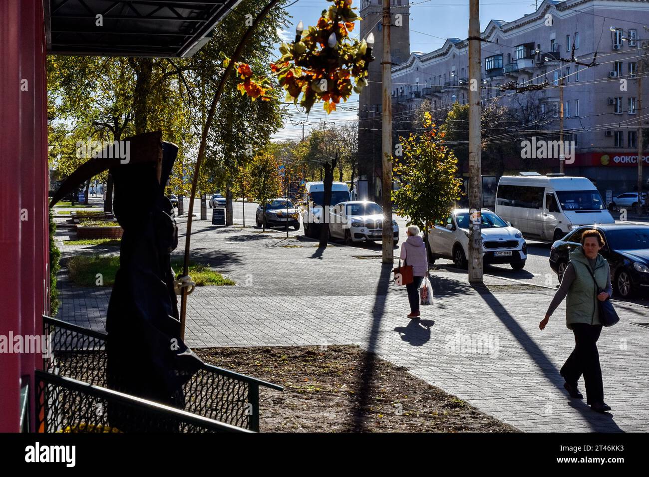 Les femmes marchent près de l'entrée du café avec des décorations d'Halloween à Zaporizhzhia. Halloween d'origine celtique est venu en Ukraine après l'effondrement de l'Union soviétique. À partir de ce moment, les Ukrainiens ont repris la tradition d'autres pays pour s'habiller en costumes effrayants, pour couper l'attribut principal de cette fête - la citrouille et pour recueillir les bonbons parmi les voisins. L'Église orthodoxe moderne condamne encore cette fête, mais chaque année en Ukraine, de plus en plus de jeunes ne sont pas contre "d'aller du côté du mal" pour une nuit. Banque D'Images