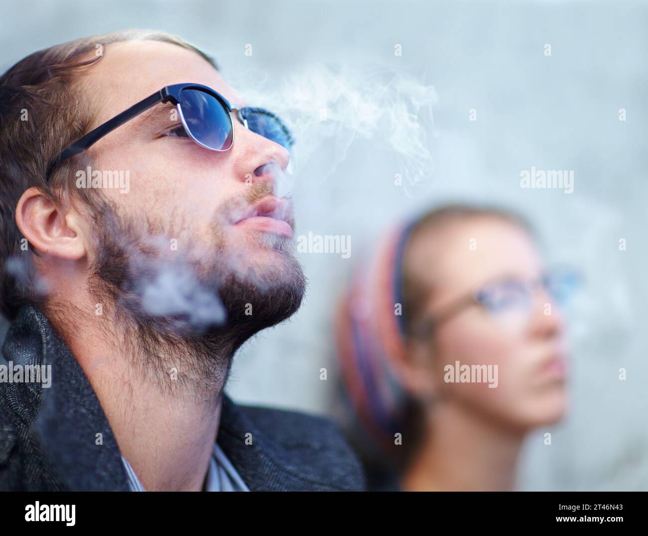Visage, homme et femme fumant en plein air avec des lunettes de soleil pour l'expérience, se détendre et profiter de la cigarette. Les gens, hipster et fumée pour tendance, expirer ou Banque D'Images