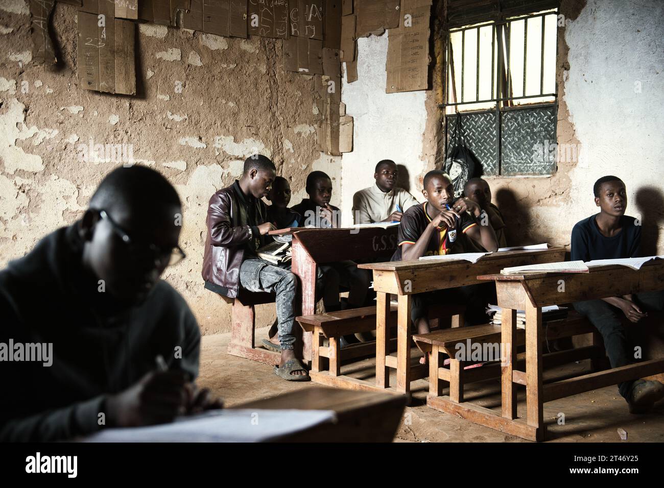 Classe de garçons et de filles dans une école rurale en Ouganda, étudient pour leurs examens de fin de trimestre dans un environnement de base Banque D'Images