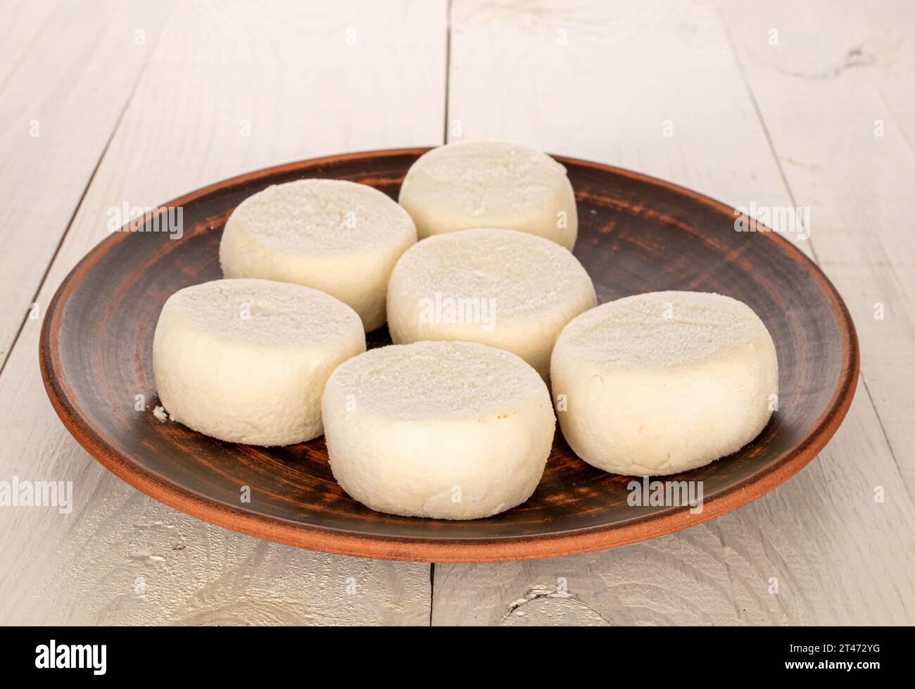 Plusieurs cheesecakes semi-finis congelés sur une assiette d'argile sur une table en bois, macro. Banque D'Images