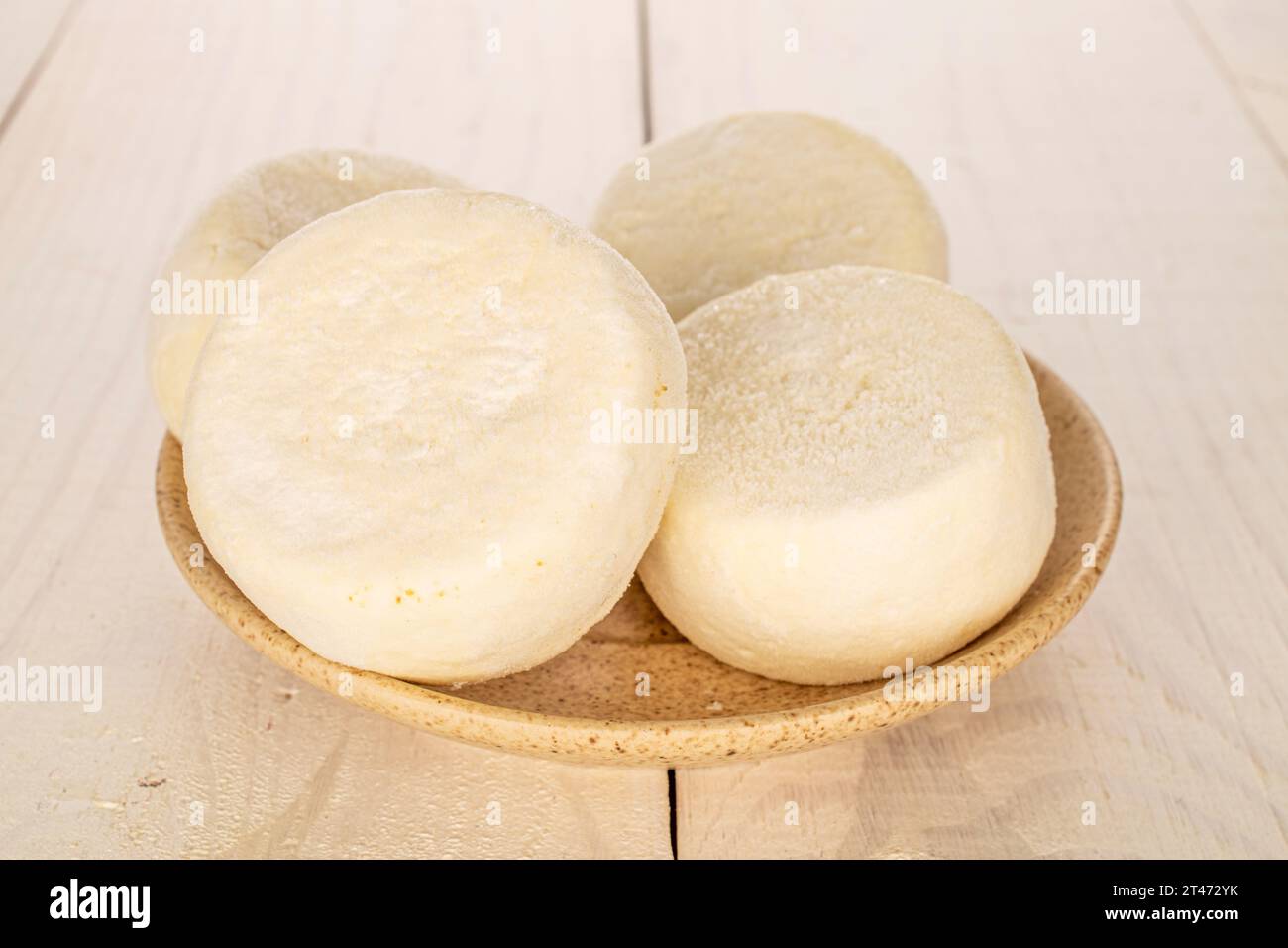 Plusieurs cheesecakes semi-finis congelés sur une soucoupe en céramique sur une table en bois, macro. Banque D'Images