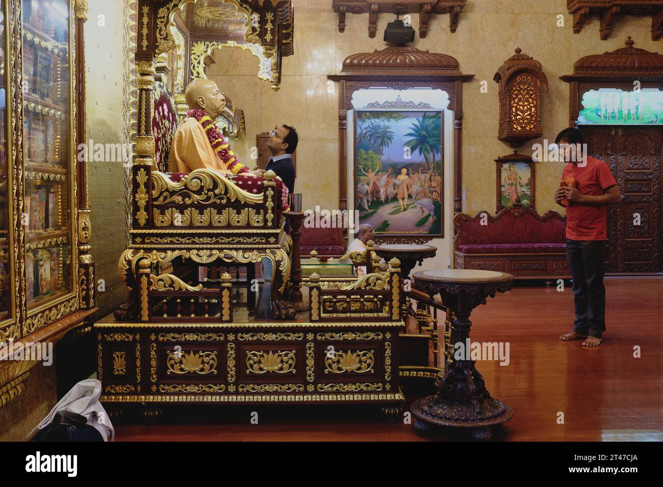 Au temple Sri Sri Radha Gopinath, Mumbai, en Inde, deux fidèles regardent avec dévotion une statue du fondateur d'ISKCON, A.C. Bhaktivedanta Swami Prabhupada Banque D'Images