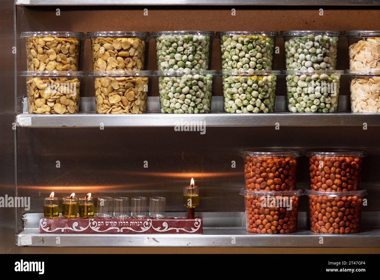 Une menorah Hanukkah inscrite avec les mots hébreux, «ces bougies, elles sont sacrées», brûle dans un magasin vendant des céréales séchées et des légumineuses dans le Machane y Banque D'Images