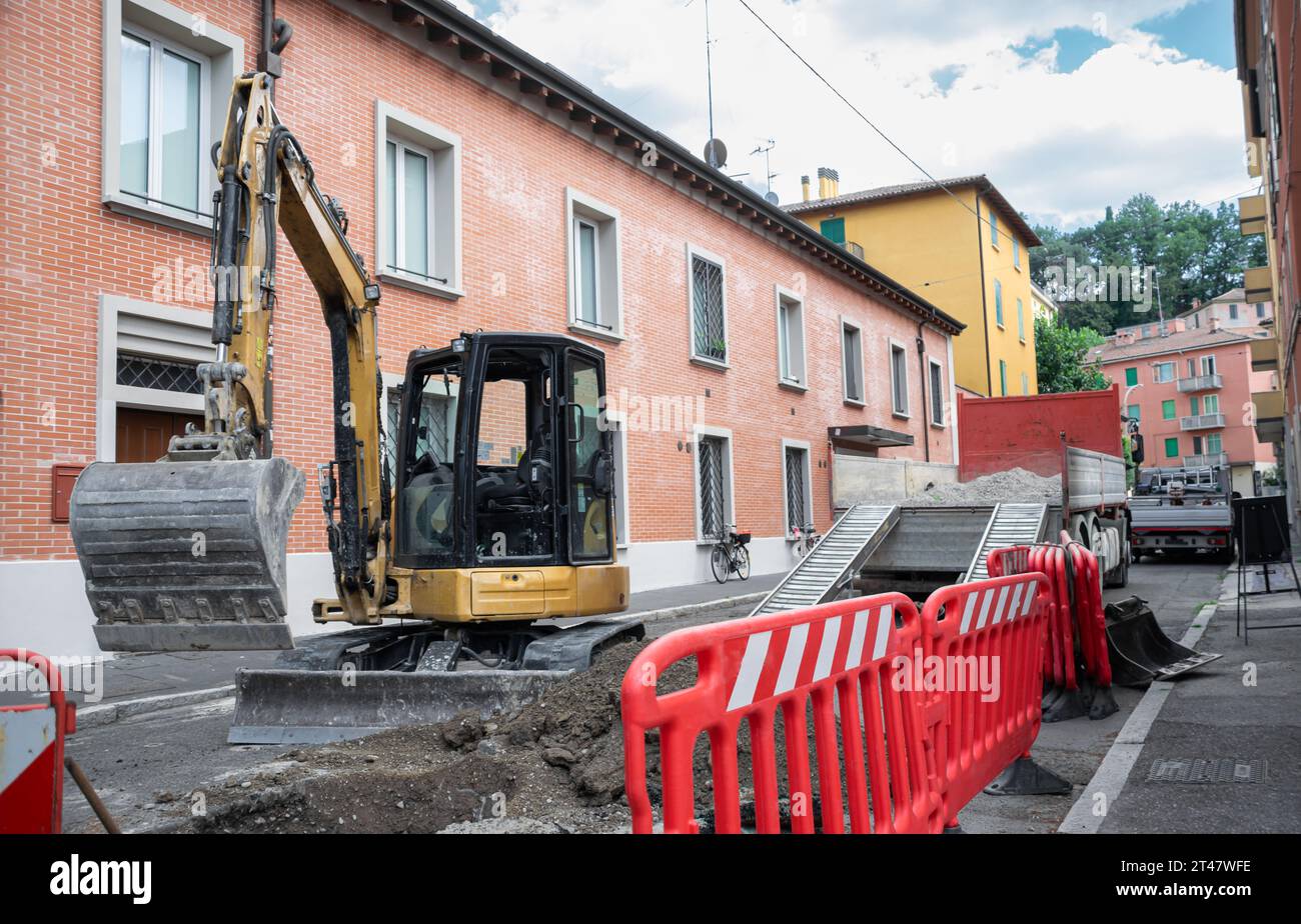 Zone de construction avec excavatrice déployée et barrières de sécurité rouges le long de la rue Banque D'Images