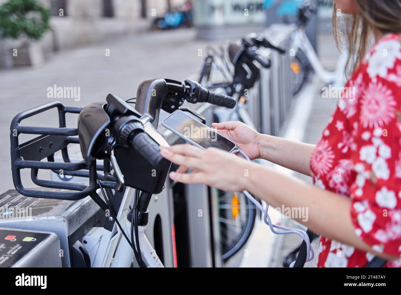 gros plan d'une jeune femme élégante utilisant l'application mobile de location de vélos, portrait d'une femme latine naviguant smartphone debout près du partage de vélos pour faire du vélo, Banque D'Images