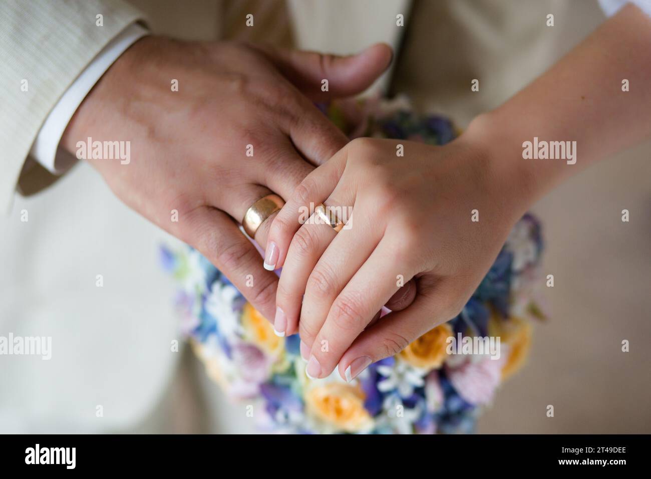 Gros plan capturant un moment d'intimité et de connexion. Il met en valeur les mains des jeunes mariés, en mettant l'accent sur les anneaux de mariage, sur le fond Banque D'Images