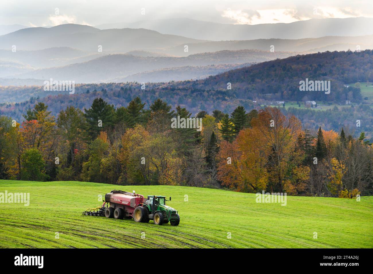 Tracteur et équipement agricole travaillant sur un champ d'automne vert dans les Green Mountains du Vermont. Banque D'Images