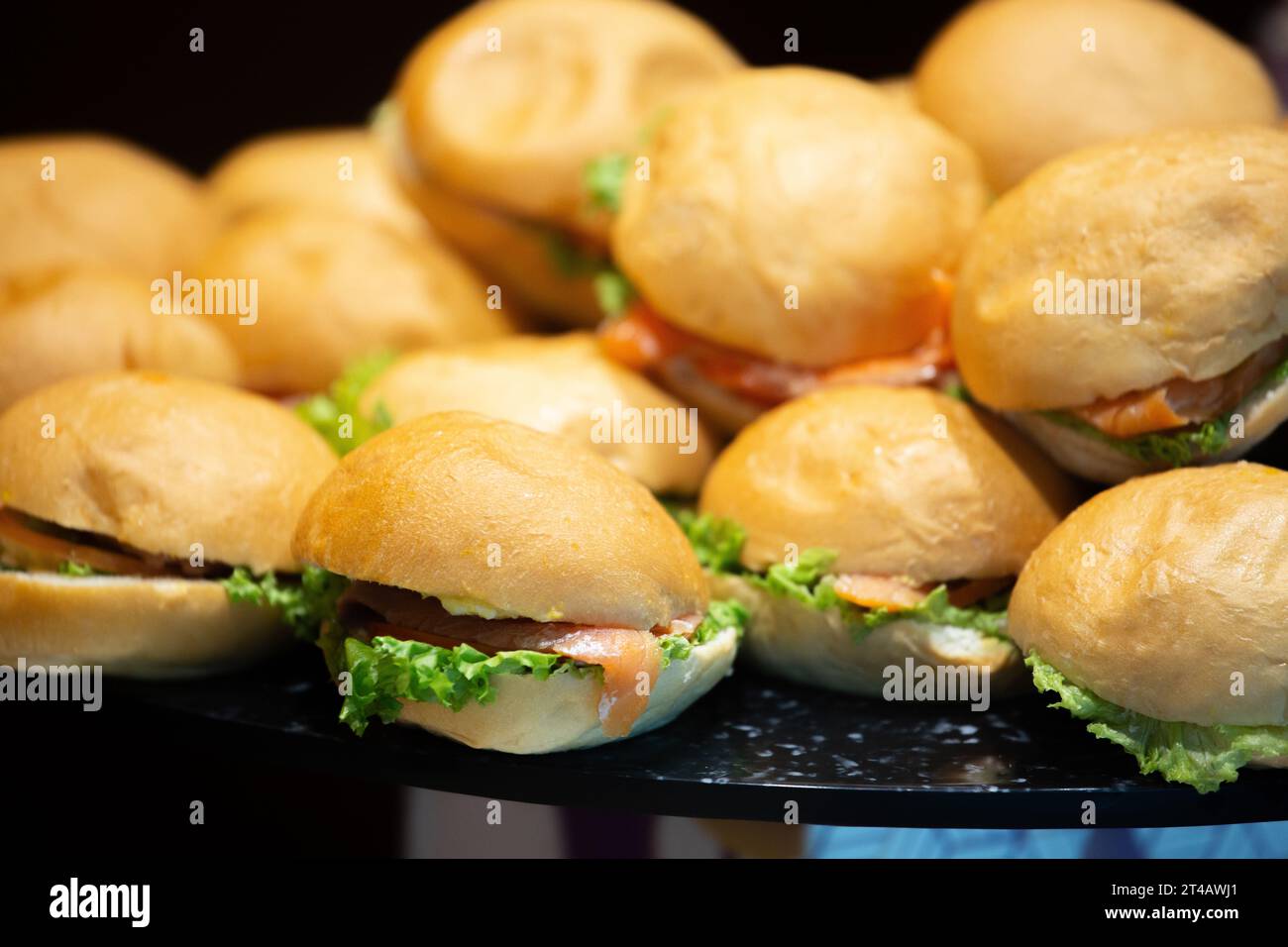 Gros plan de petits petits pains fraîchement préparés fourrés de saumon fumé, de tomate et de laitue, parfaits pour les fonctions alimentaires, les menus ou une utilisation éditoriale. Banque D'Images