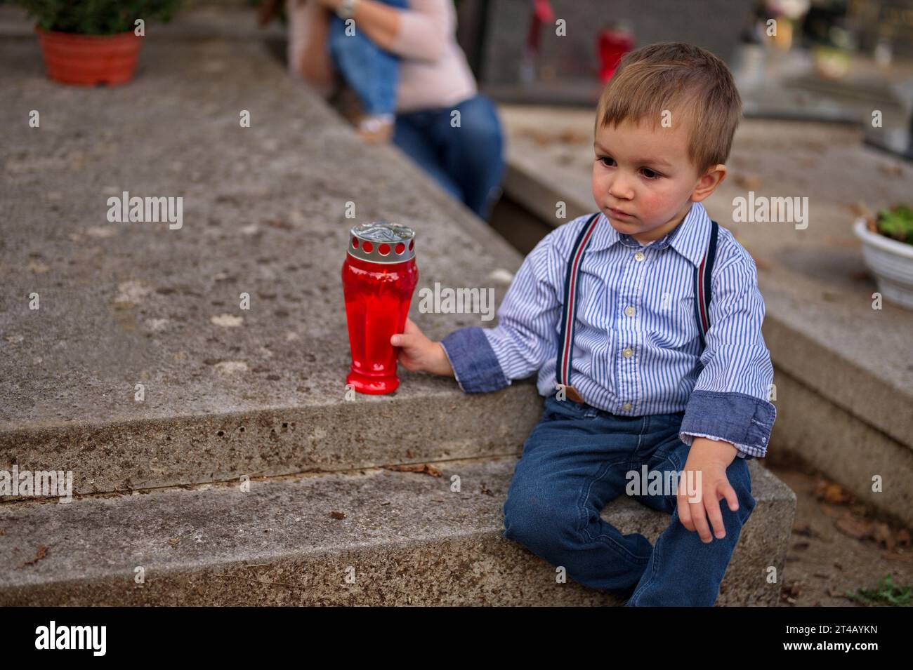 Petit enfant tenant une bougie sur la tombe Banque D'Images