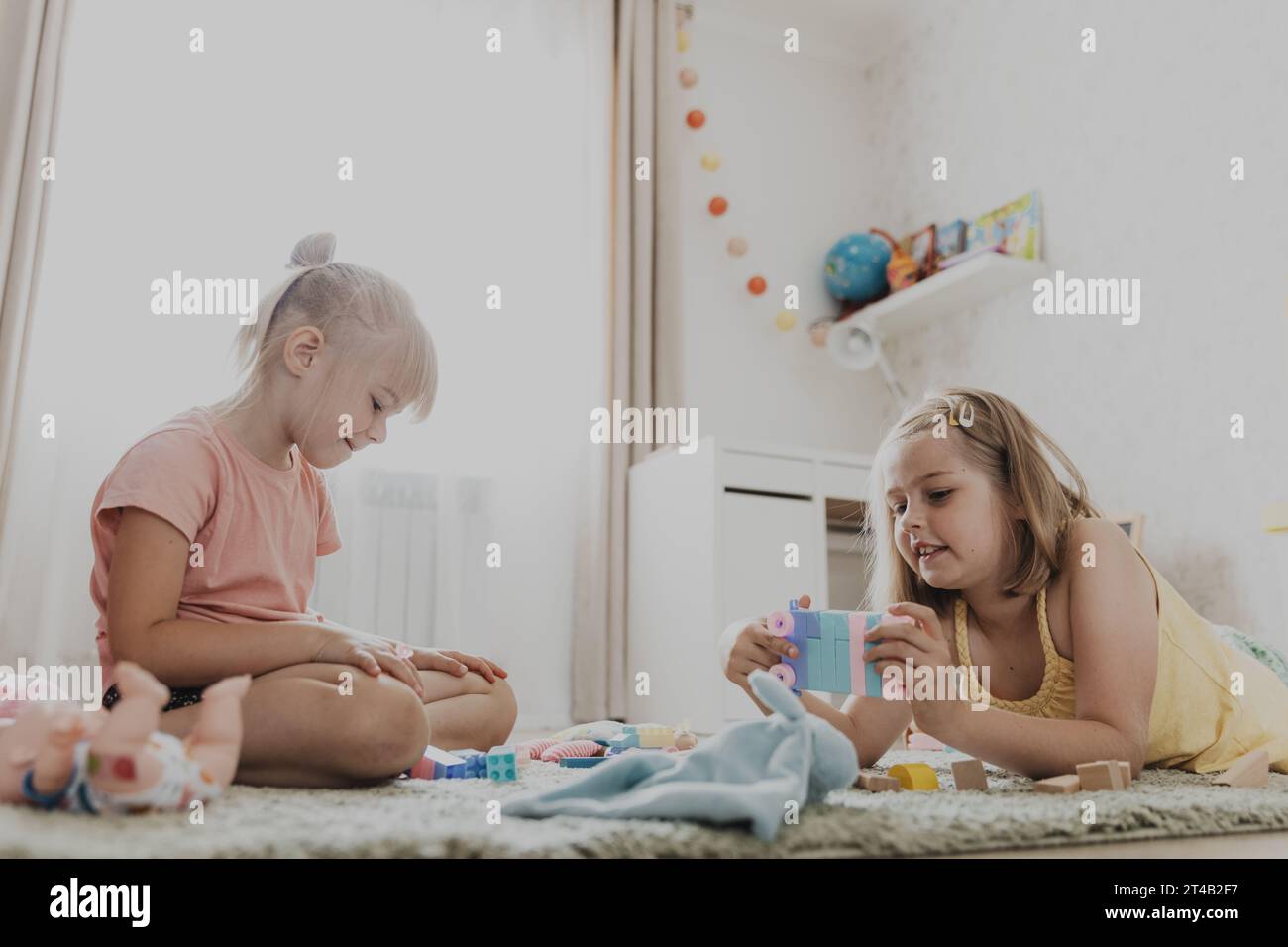 Enfants jouant avec des jouets colorés. Enfants assis sur la moquette dans la chambre à coucher ou la maternelle à la maison, la crèche. Jeu écologique éducatif pour enfant. Sœurs douces créatives concentrées d'âge préscolaire Banque D'Images