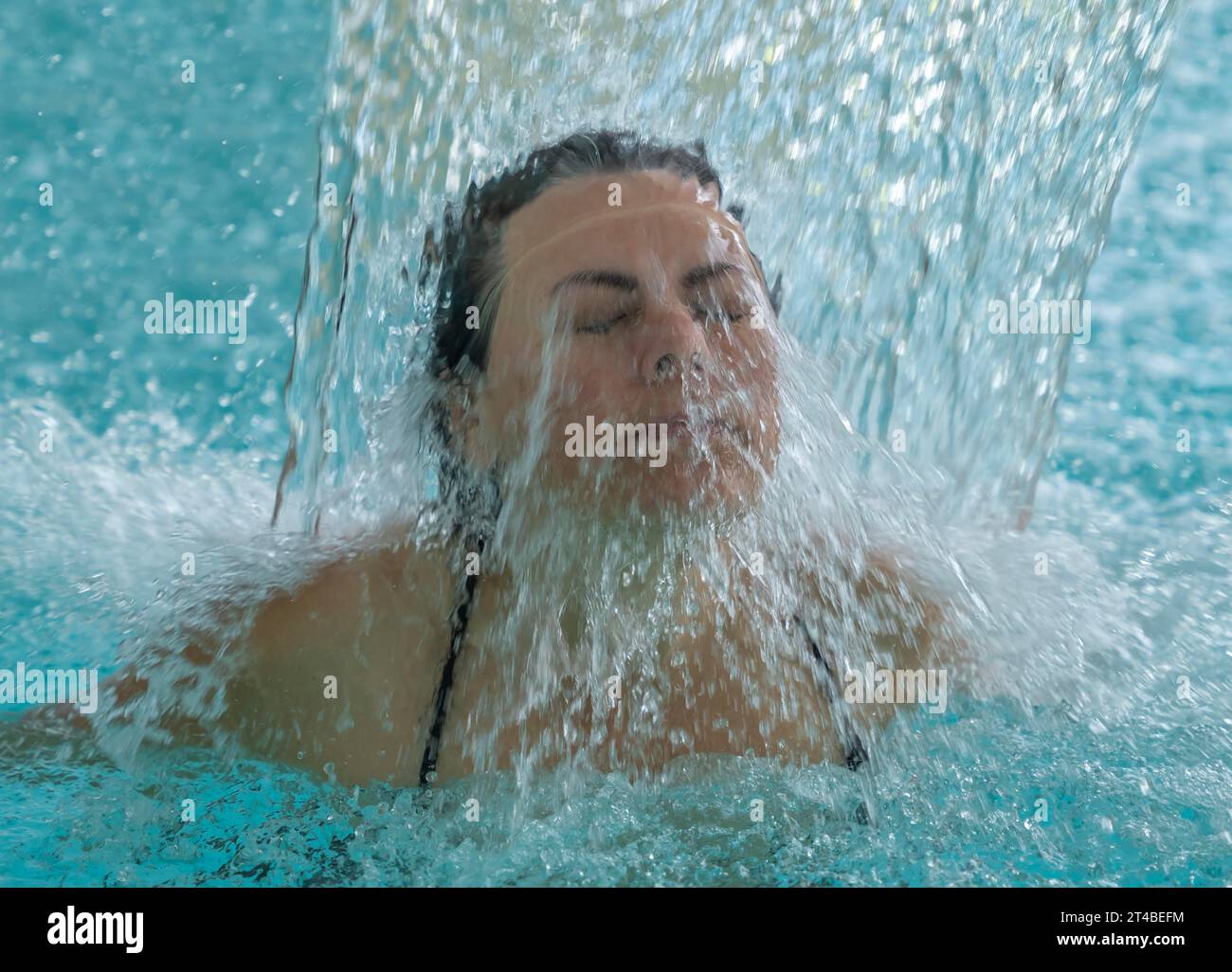 Visage de femme avec les yeux fermés profitant dans une cascade dans une piscine SPA en Suisse Banque D'Images