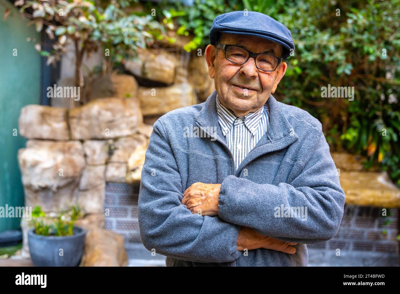 Homme âgé fier avec béret debout avec les bras croisés dans un gériatrique Banque D'Images