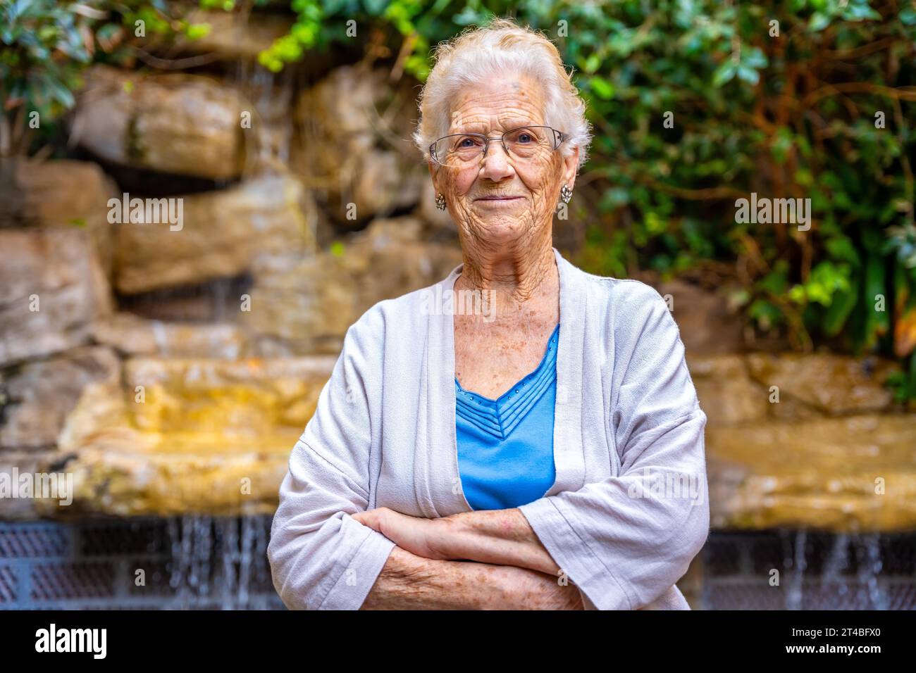 Fière femme aînée regardant la caméra dans le jardin d'une maison de retraite Banque D'Images