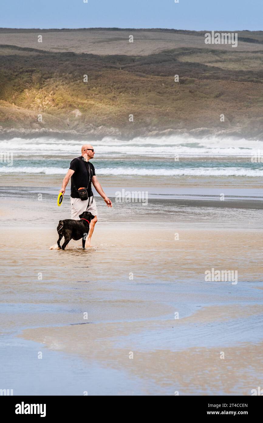 Un homme jouant avec son chien de compagnie sur Crantock Beach à Newquay en Cornouailles au Royaume-Uni. Banque D'Images