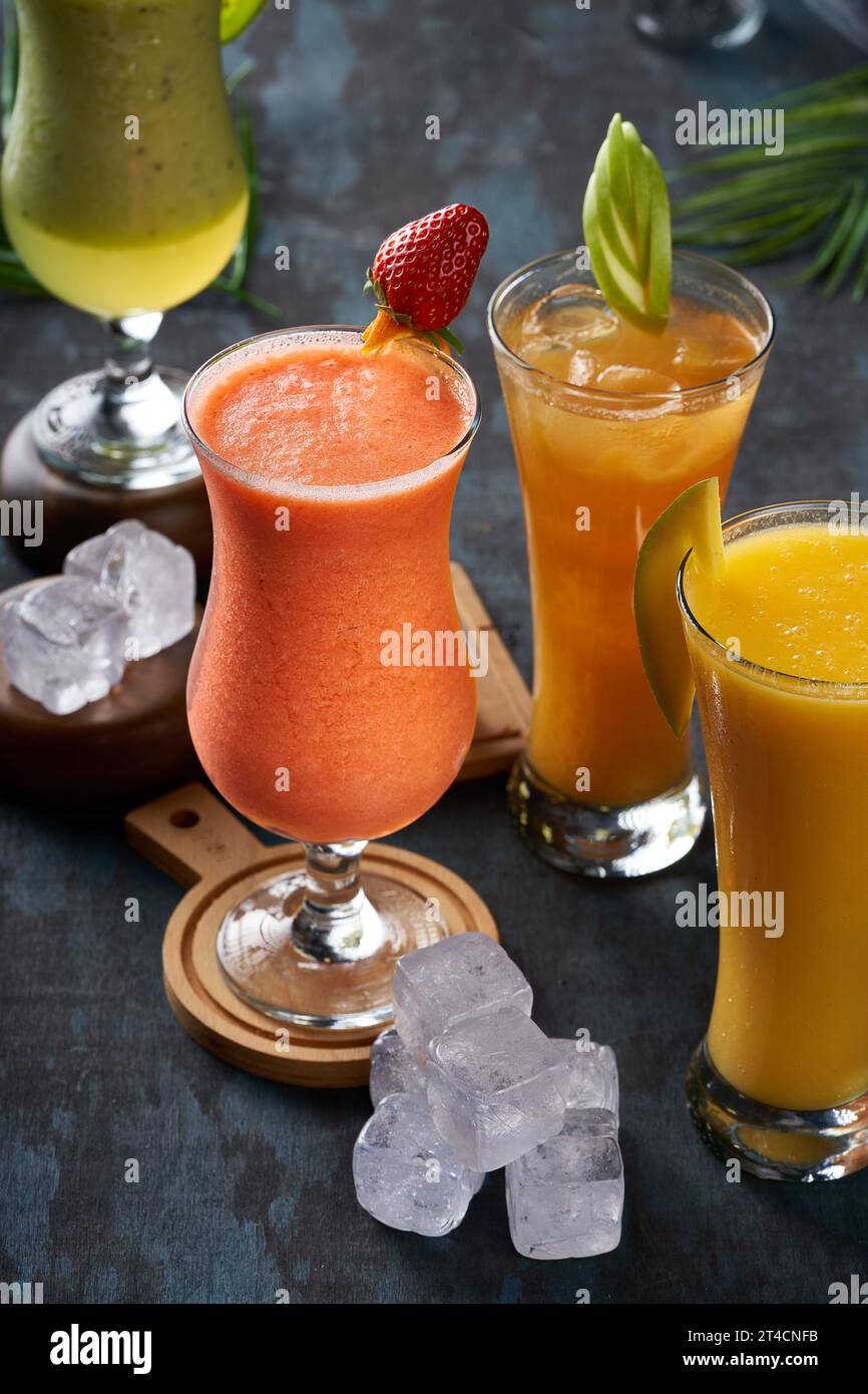 Un groupe de verres à jus assortis avec des glaçons sur un plancher en bois Banque D'Images