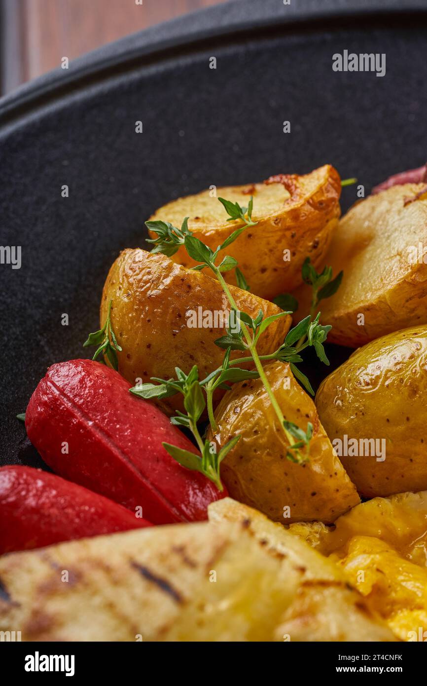 Gros plan d'une assiette d'œufs au plat avec bacon, saucisse et pommes de terre cuites au four Banque D'Images