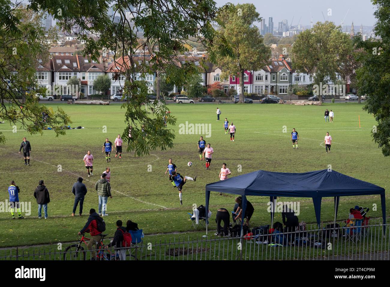 Avec la ville au loin, les joueurs de football amateur jouent un match dans une ligue hispanophone à Ruskin Park, un espace vert public à Lambeth au sud de Londres, le 28 octobre 2023, à Londres, en Angleterre. Banque D'Images