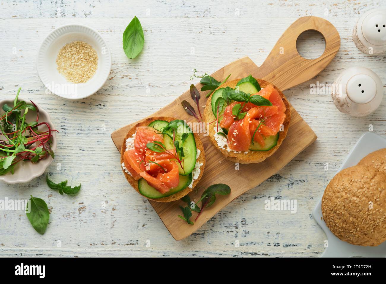 Sandwichs ouverts au saumon fumé avec fromage à la crème, concombre, graines de sésame, microgreens, épinards, et les feuilles de pois sur fond de bois vieux clair. Sain Banque D'Images