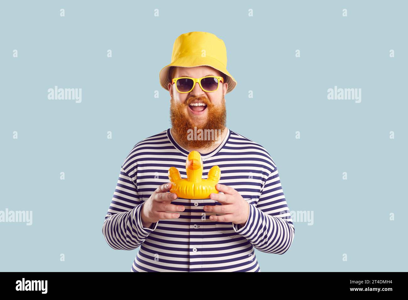 Homme Chubby drôle avec petit canard gonflable jouet sur fond bleu clair pastel. Banque D'Images