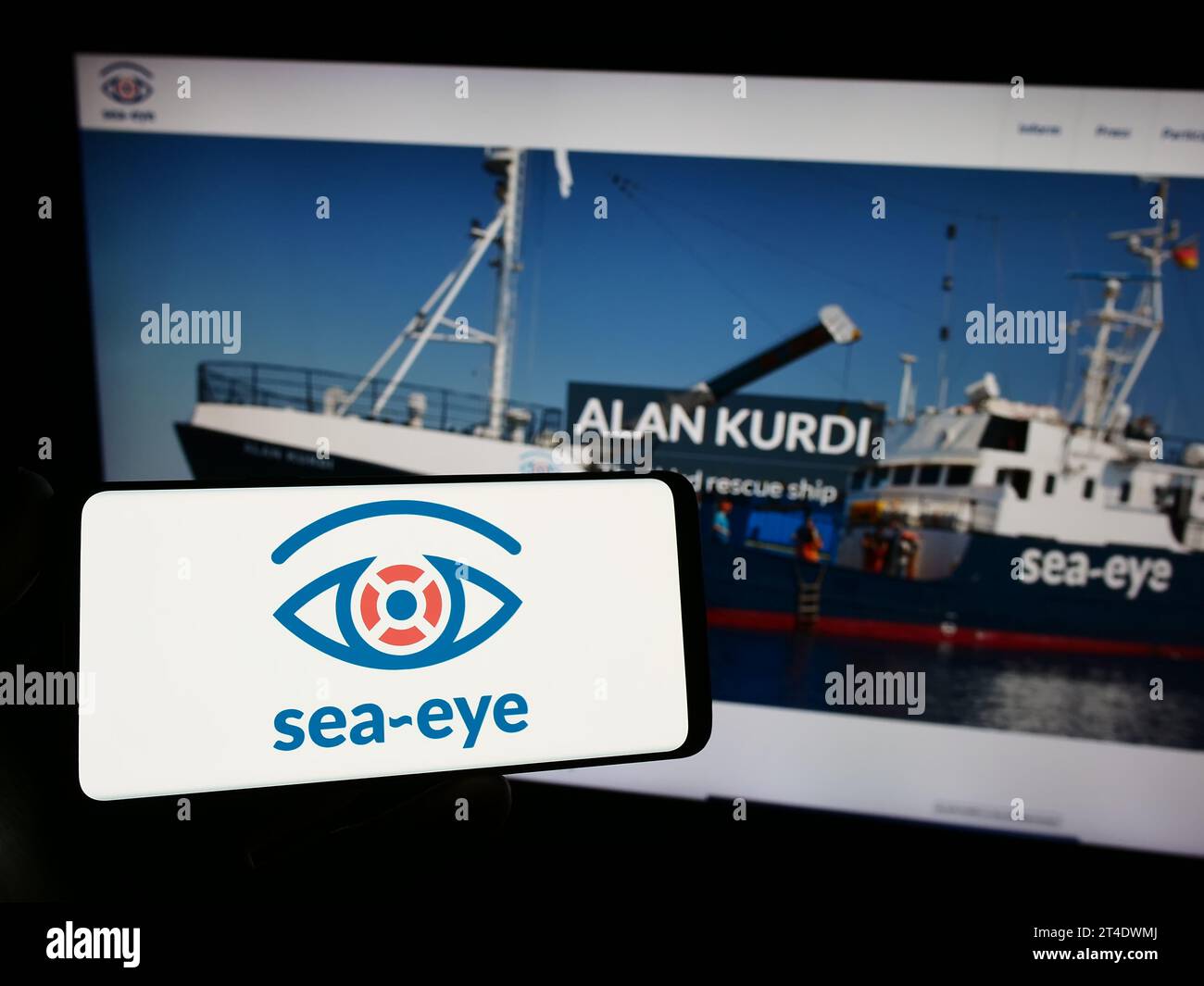 Personne tenant un smartphone avec le logo de l'association allemande de sauvetage en mer Sea-Eye e.V. devant le site Web. Concentrez-vous sur l'affichage du téléphone. Banque D'Images