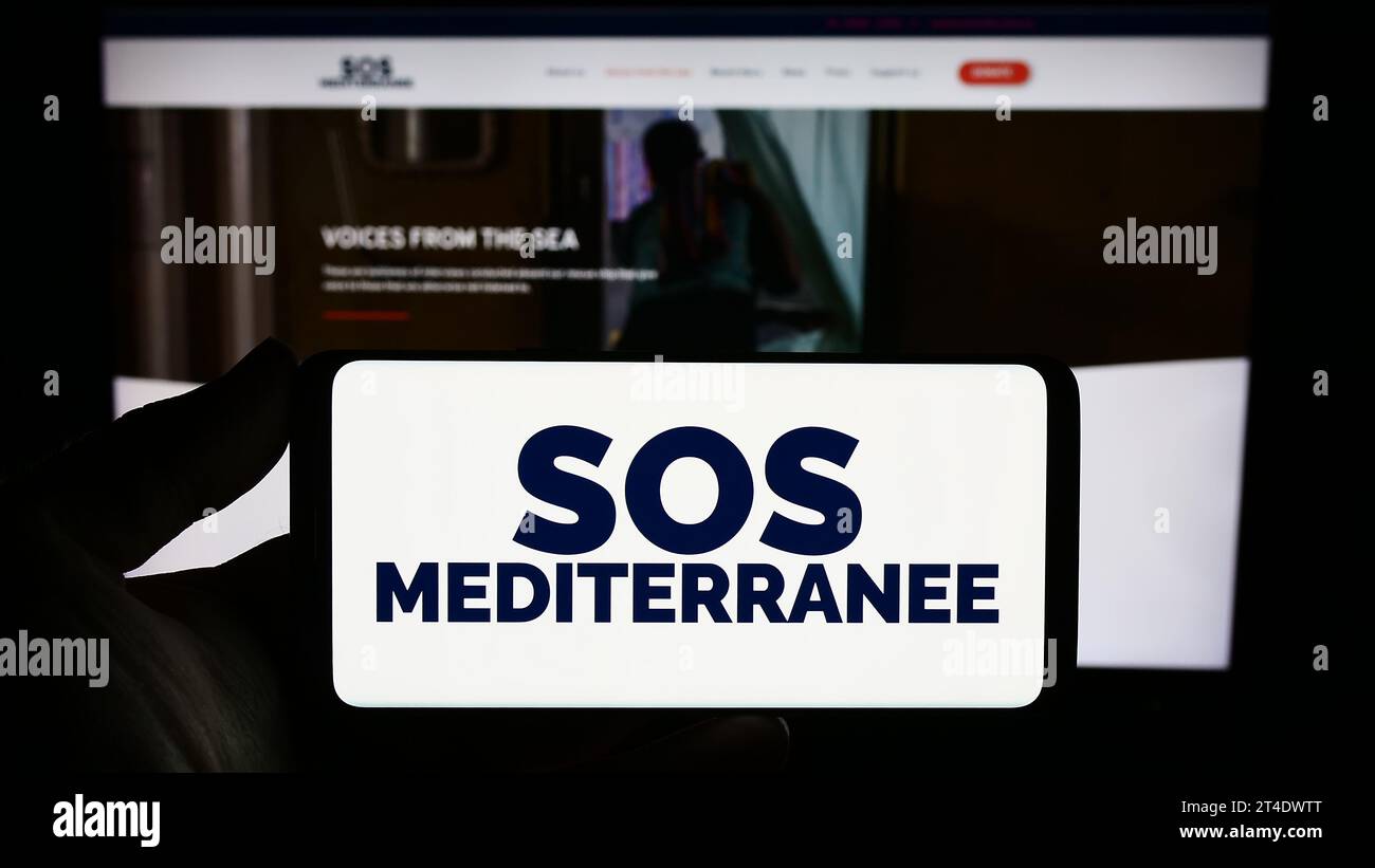 Personne détenant un smartphone avec le logo de l'organisation française de sauvetage en mer SOS Mediterranee devant le site web. Concentrez-vous sur l'affichage du téléphone. Banque D'Images