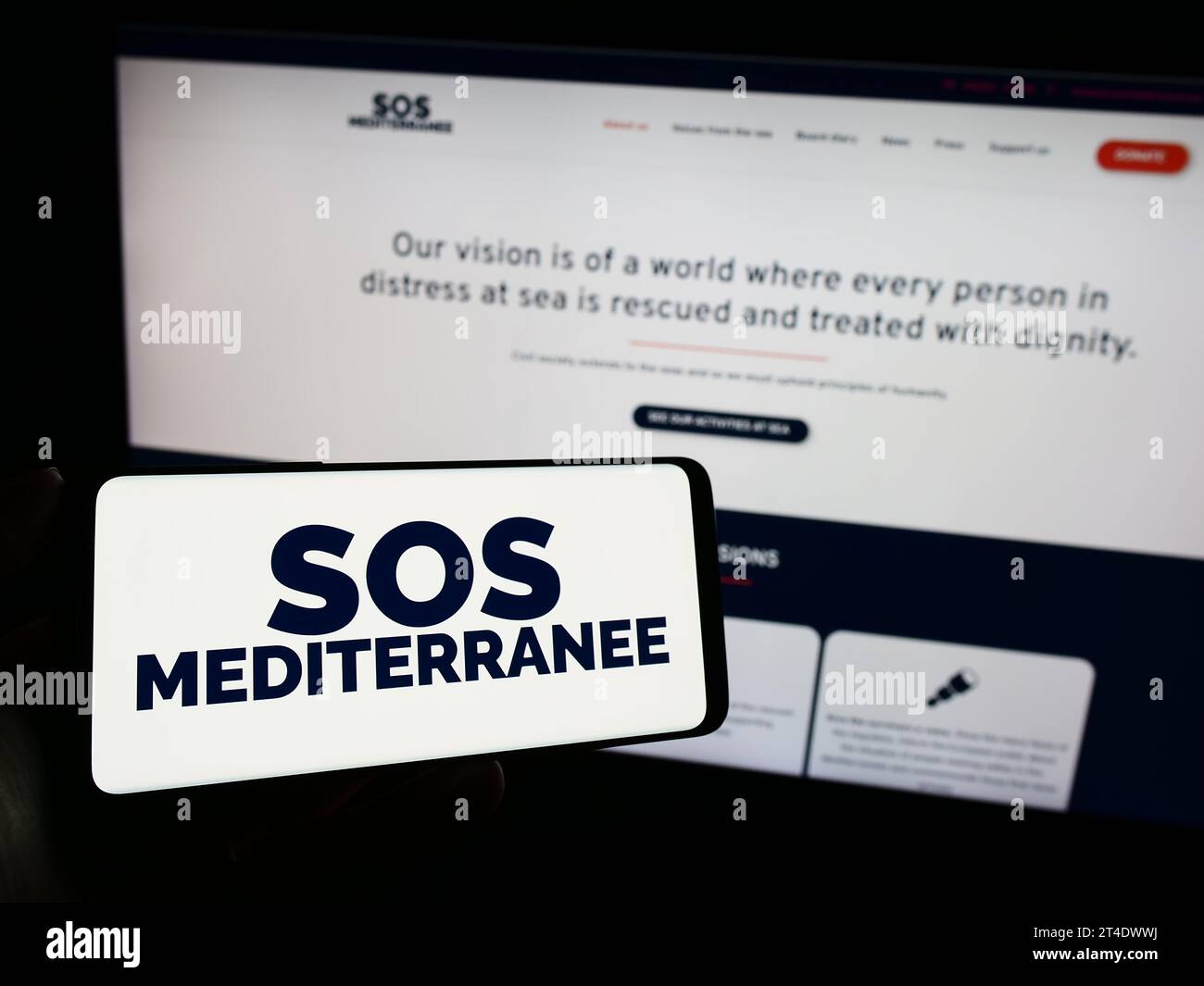 Personne tenant un téléphone portable avec le logo de l'organisation française de sauvetage en mer SOS Mediterranee devant la page web. Concentrez-vous sur l'affichage du téléphone. Banque D'Images