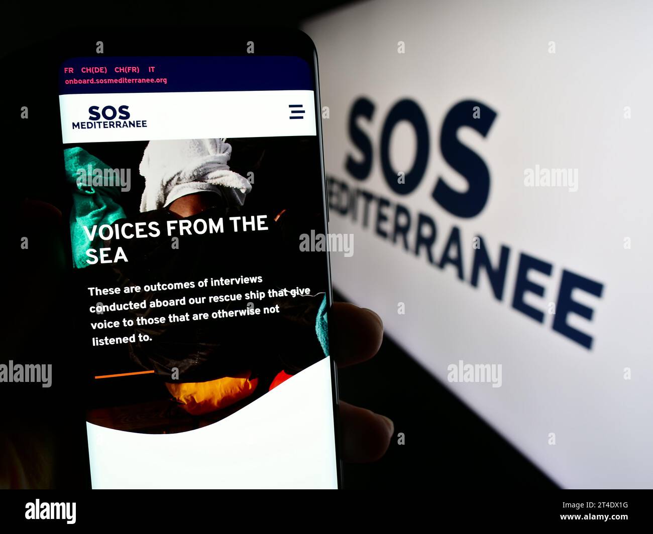 Personne détenant un téléphone portable avec la page web de l'organisation française de sauvetage en mer SOS Mediterranee devant le logo. Concentrez-vous sur le centre de l'écran du téléphone. Banque D'Images