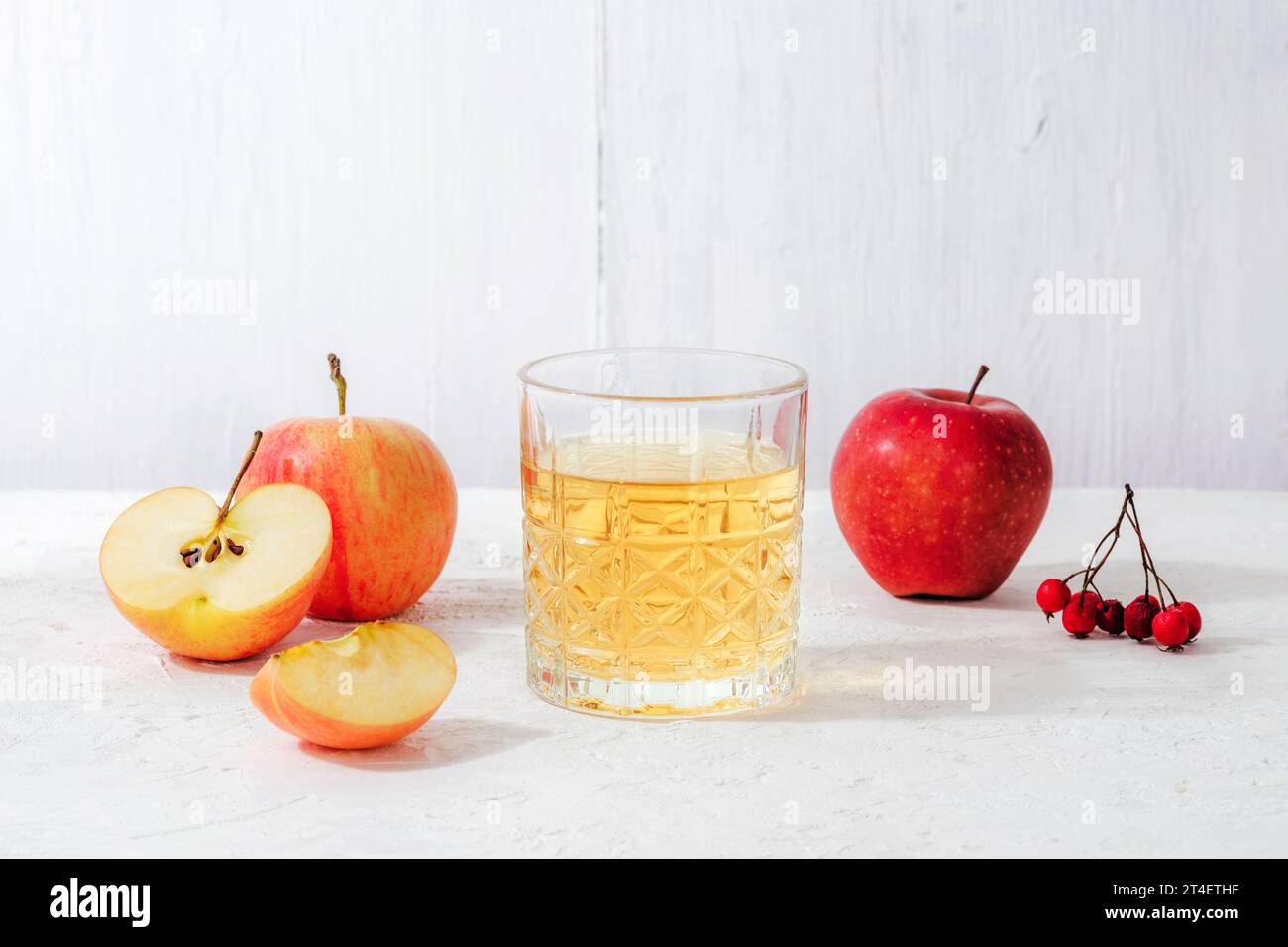 Pommes mûres fraîches et verre de jus de pomme ou de cidre sur la table blanche. Récolte d'automne, concept de Thanksgiving. Banque D'Images