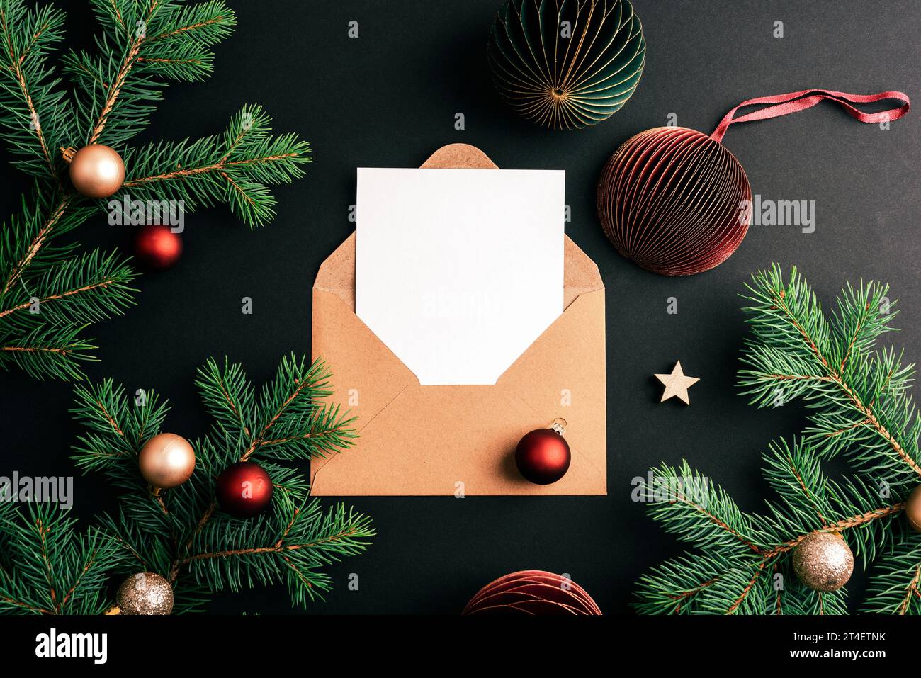 Enveloppe avec carte vierge et branches de sapin avec boules de Noël sur fond noir. Concept de Noël. Vue de dessus, pose à plat, maquette. Banque D'Images