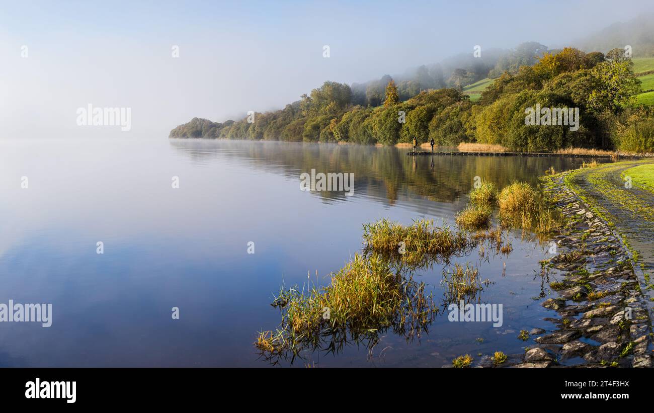 Un panorama multi-images de deux hommes pêchant sur le lac Bala alors que la brume se lève lentement autour d'eux révélant des reflets étonnants dans l'eau. Banque D'Images