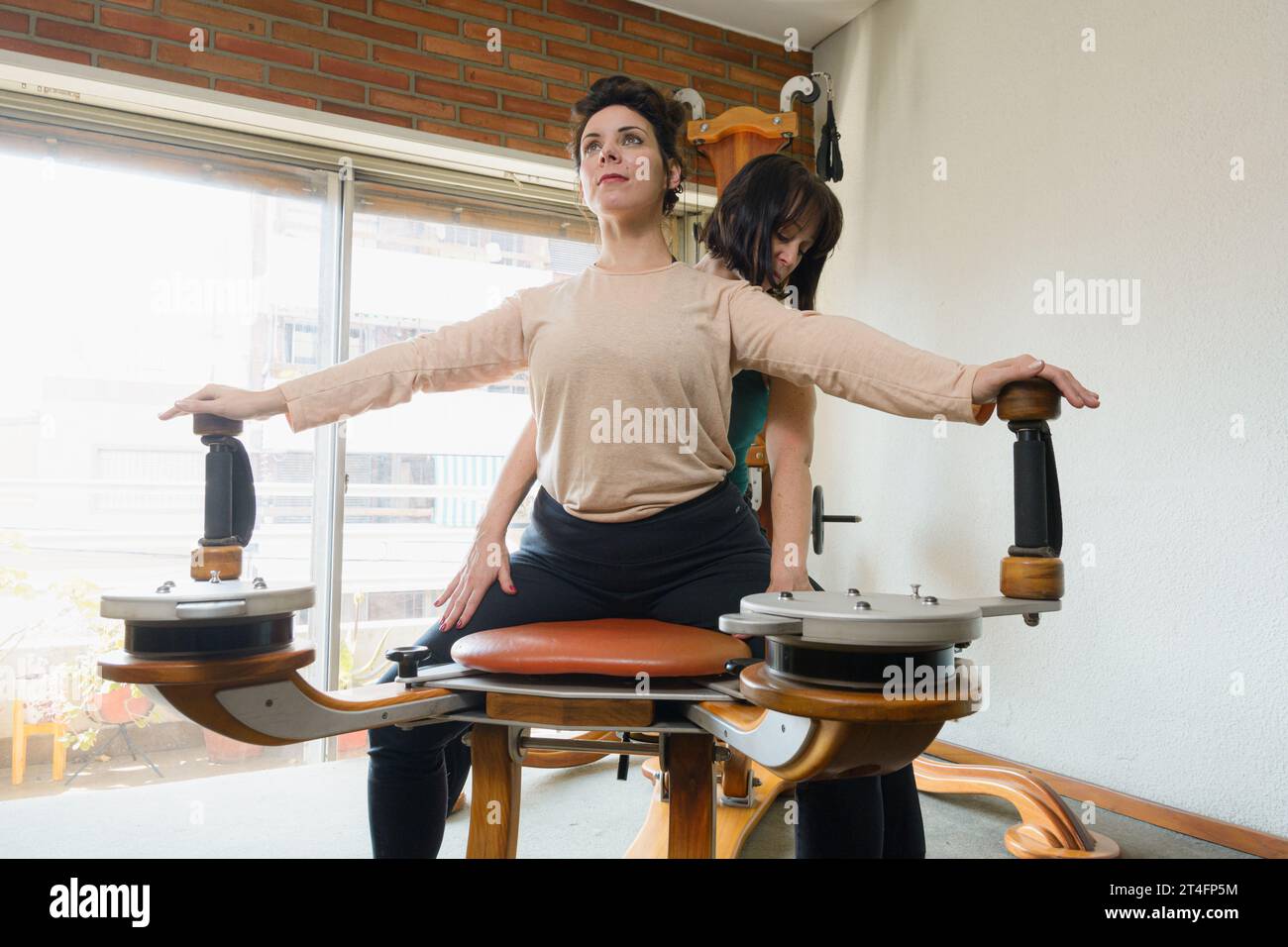 Enseignante enseignant à son étudiante la technique correcte de l'exercice sur la machine de réadaptation pour renforcer et améliorer la santé articulaire. Banque D'Images