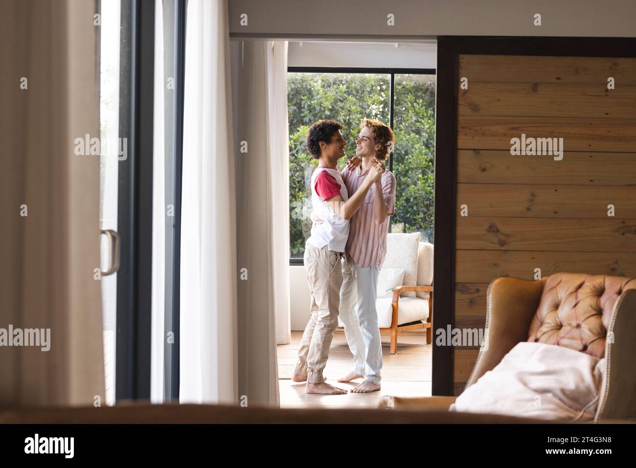 Heureux couple masculin gay diversifié avec cheveux bouclés dansant à la maison Banque D'Images