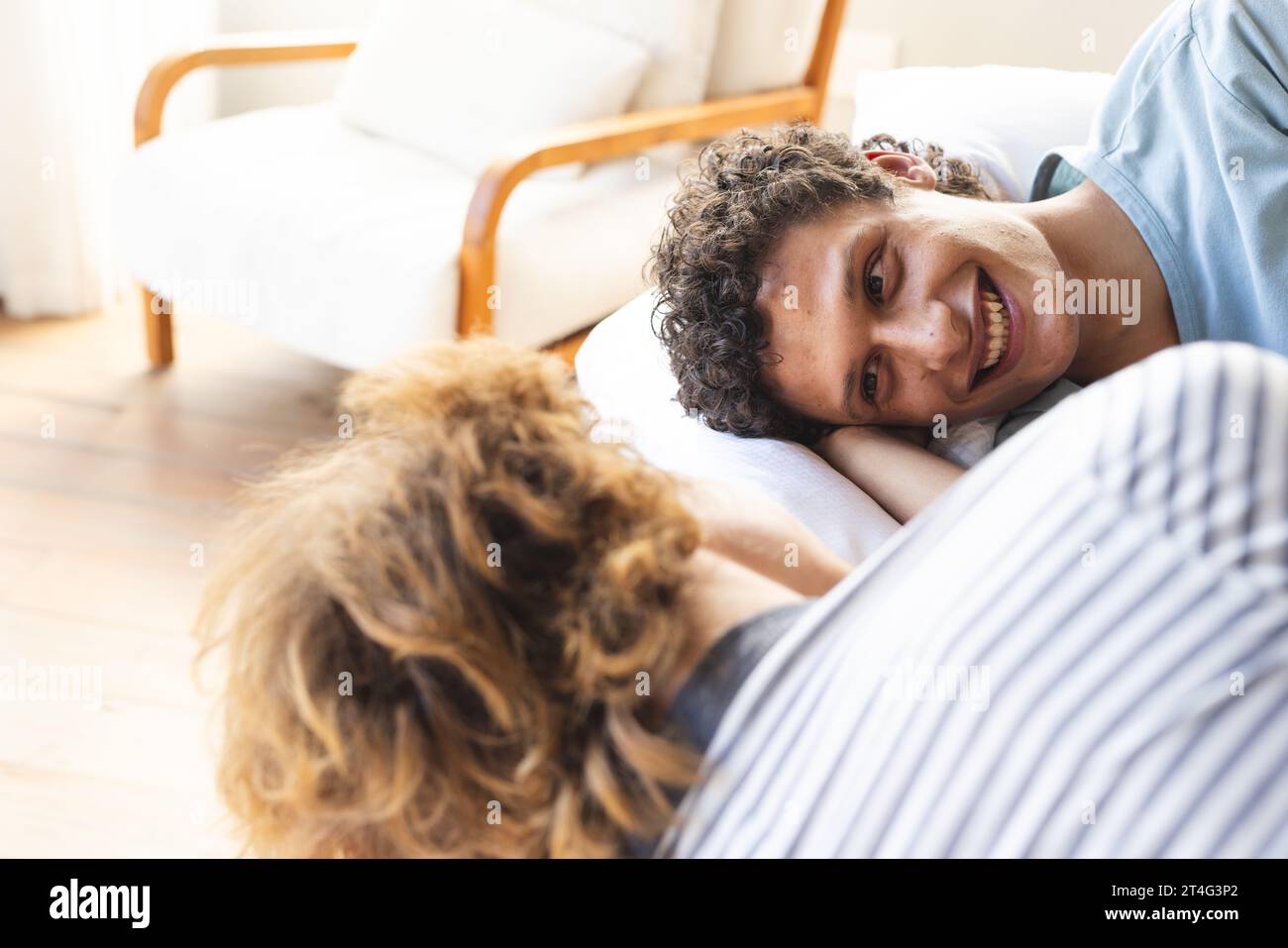 Heureux et diversifié couple masculin gay couché sur le lit et se regardant à la maison Banque D'Images