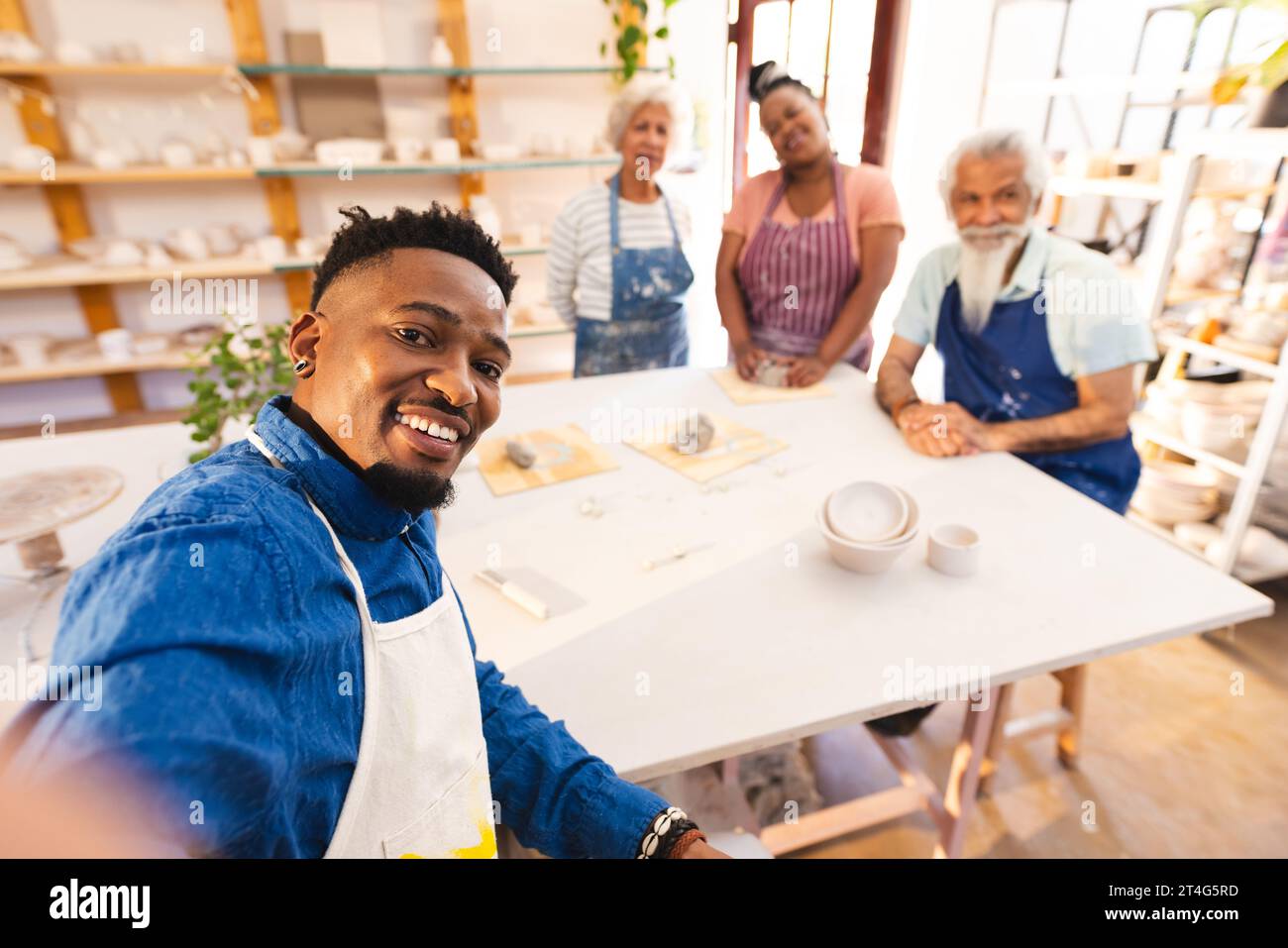 Heureux potier afro-américain faisant selfie lui-même et d'autres dans le studio de poterie Banque D'Images