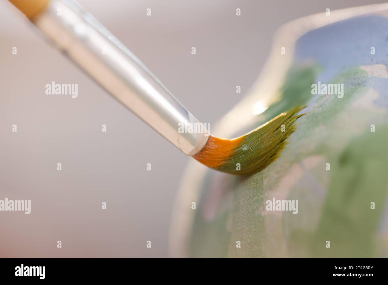 Gros plan de la cruche d'argile de peinture de pinceau dans l'atelier de poterie Banque D'Images