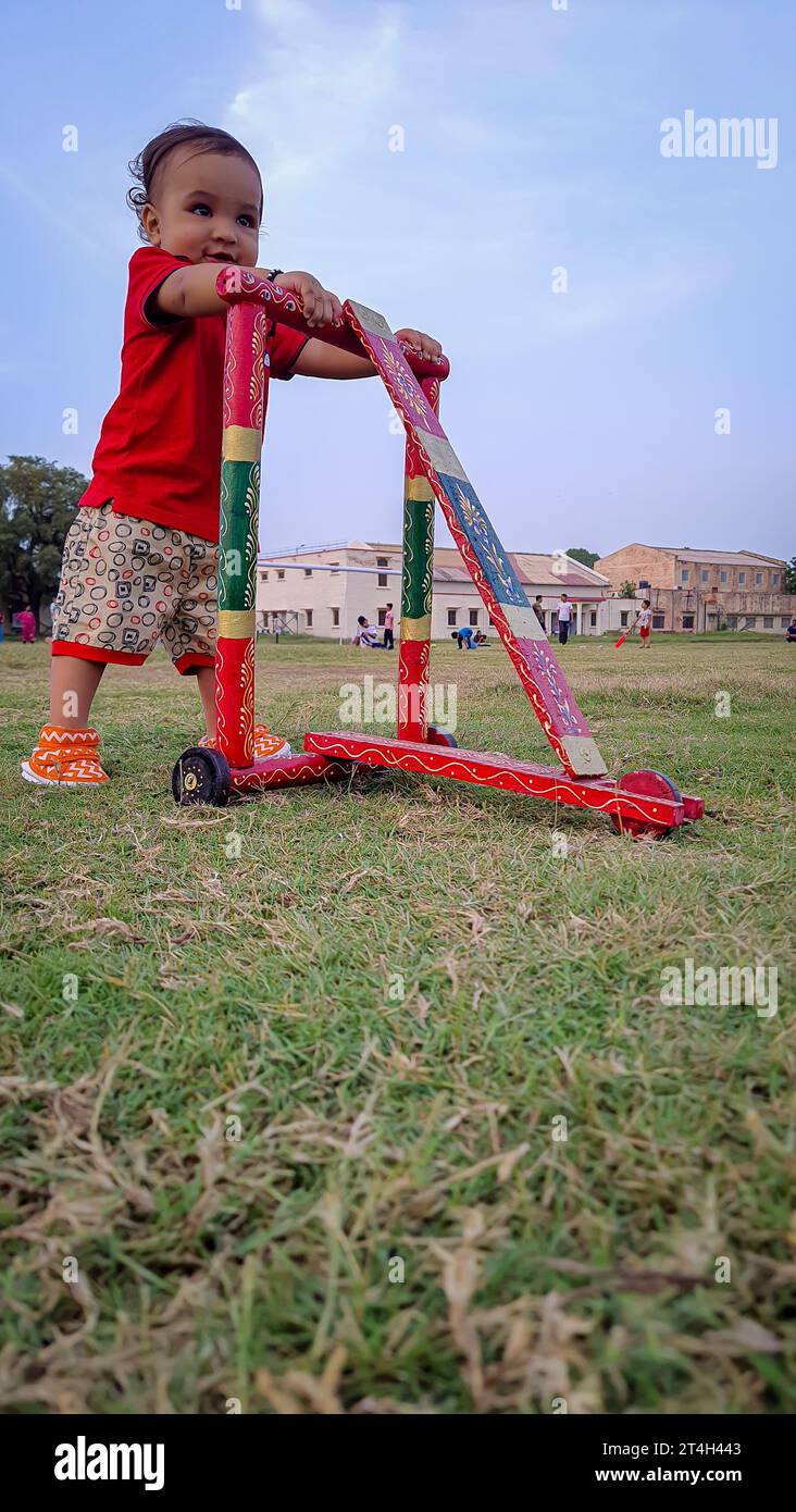 tout-petit apprenant la marche sur marcheur en bois traditionnel à l'extérieur sous un angle différent Banque D'Images