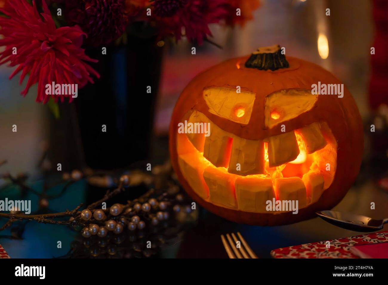 Citrouille d'Halloween sculptée avec un visage toothy et des bougies à l'intérieur sur une table à manger Banque D'Images