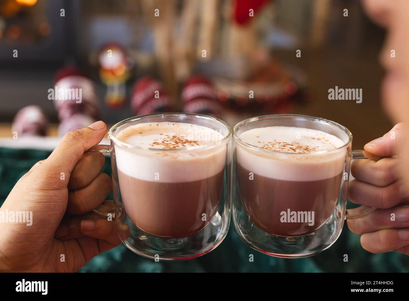 Couple masculin gay diversifié tenant des verres de cacao et portant des vêtements de noël à la maison Banque D'Images