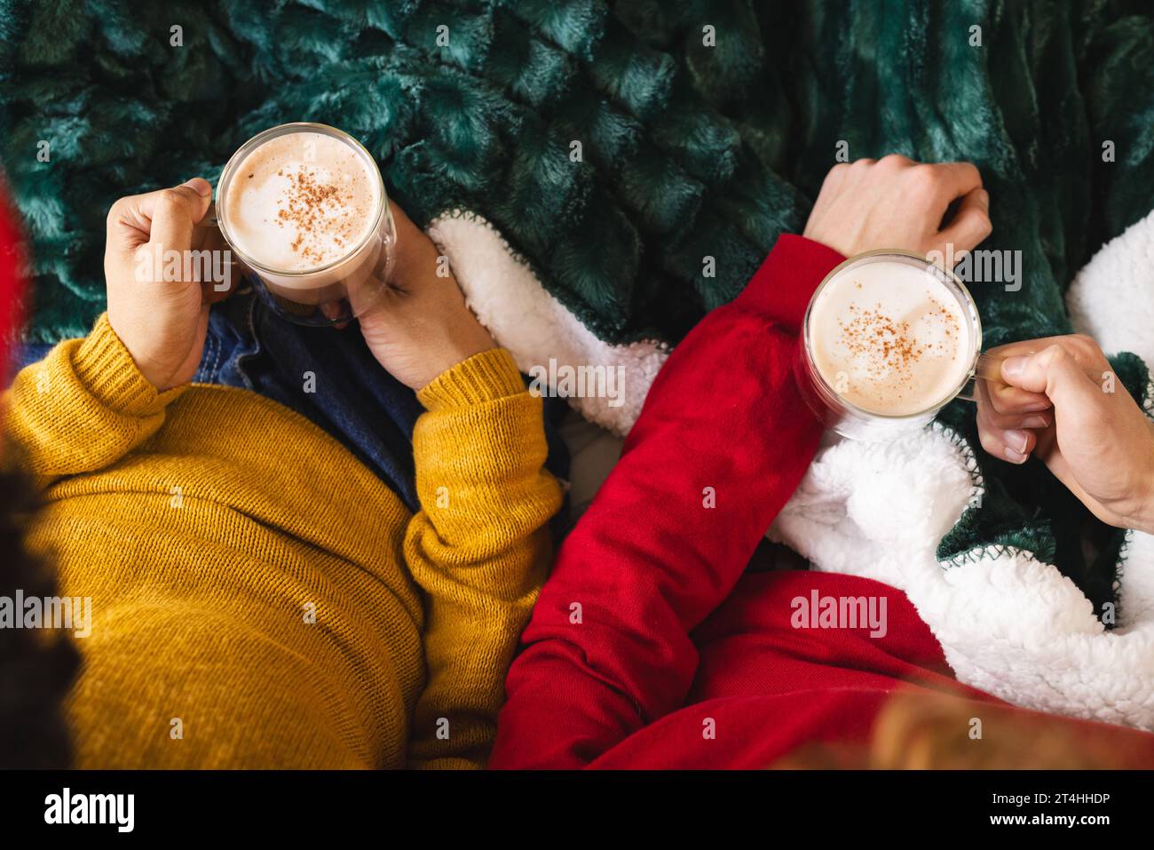 Couple masculin gay diversifié tenant des verres de cacao recouverts de couverture à la maison Banque D'Images