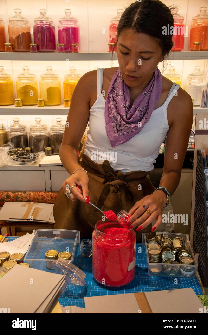 Une directrice de boutique remplit une petite quantité de pigment de couleur pure à l'aide d'une petite cuillère dans un petit pot dans sa boutique d'art à Venise, dans la région vénitienne o Banque D'Images