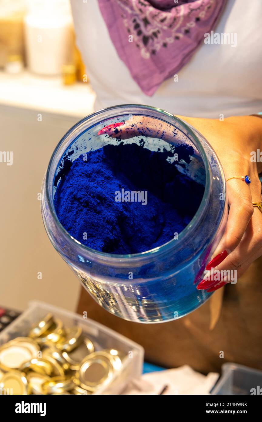 Une directrice de boutique remplit une petite quantité de pigment de couleur pure à l'aide d'une petite cuillère dans un petit pot dans sa boutique d'art à Venise, dans la région vénitienne o Banque D'Images