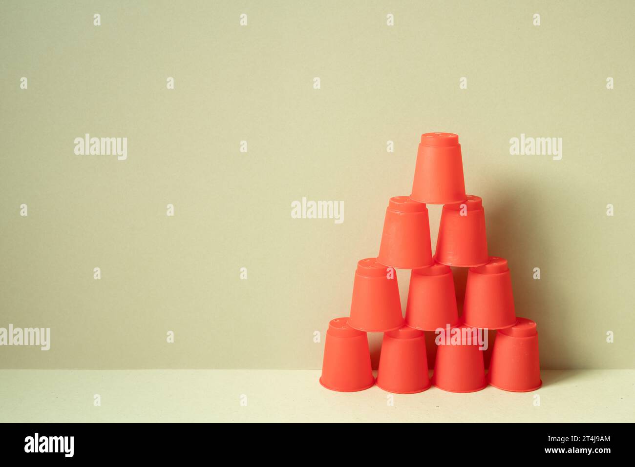 Pyramide de gobelets en plastique rouge sur le bureau. fond beige kaki. travail d'équipe équilibre affaires développer le concept de croissance de réalisation Banque D'Images
